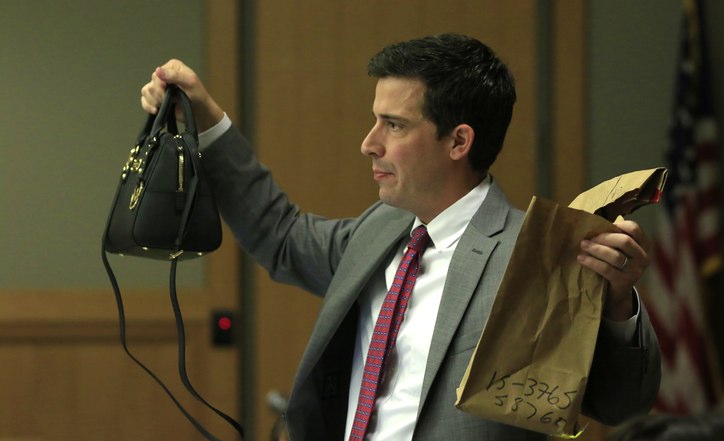 Cody holding the handbag and the paper bag for evidence